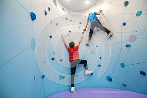 Boy hanging on wall lending helping hand to friend