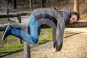 Boy hanging on a wooden structure in a park