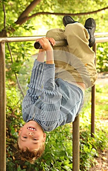 Boy hangs on bars headfirst