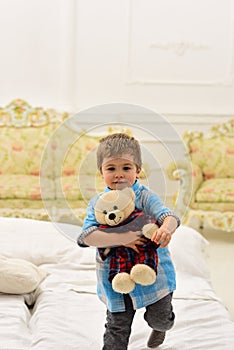 Boy with happy face holds favourite toy fluffy bear. Child with soft teddy bear in hands. Kid play with plush bear