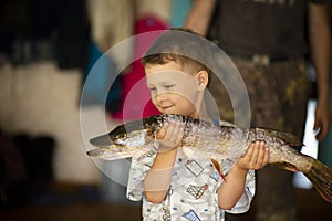 boy happy little fisherman with big hand pike