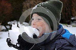 Happy wintertime, boy tastes with his tongue the snow photo