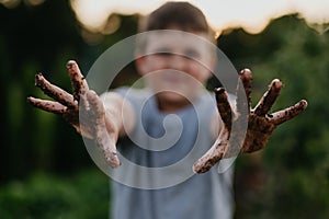 Boy has dirty hands after work in garden. Caring for vegetable garden and growing, planting spring vegetables.