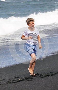 Boy has fun at the black volcanic beach