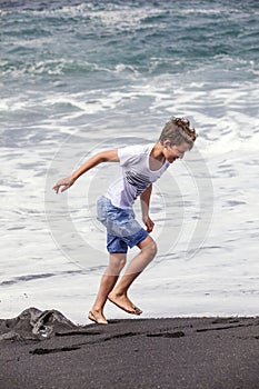 Boy has fun at the black volcanic beach