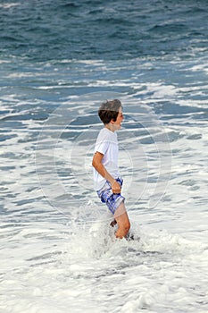 Boy has fun in the spume at the black beach