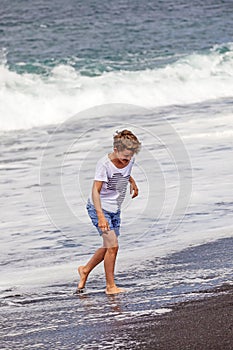 Boy has fun in the spume at the black beach