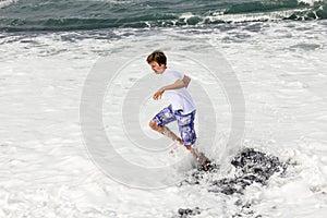 Boy has fun in the spume at the black volcanic beach