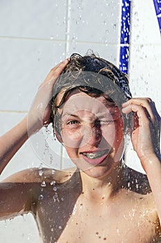 Boy has fun unter the pool shower