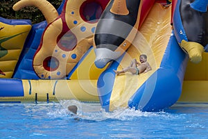 Boy has into pool after going down water slide during summer. little boy sliding down water slide and having