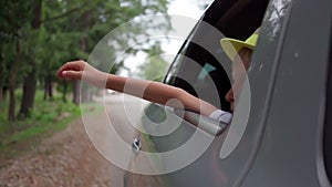 boy in hat waves from traveling car outside city. Traveling by car. Freedom, vacation. pleasure of relaxation. long trip