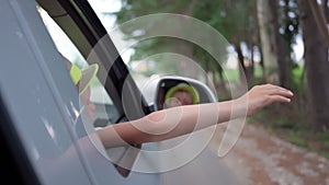 boy in hat waves from traveling car outside city. Traveling by car. Freedom, vacation. pleasure of relaxation. long trip