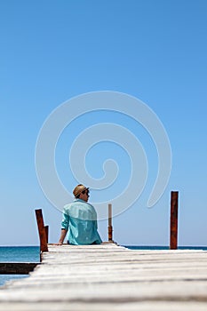 boy with hat on wooden pier over the sea