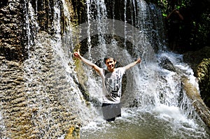 Boy having fresh under waterfall