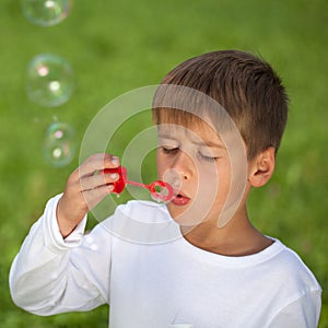 Boy having fun with bubbles on a green meadow