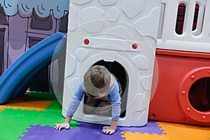 Boy having fun in kids amusement park and indoor play center. Child playing with colorful toys in playground.