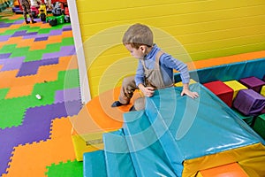 Boy having fun in kids amusement park and indoor play center. Child playing with colorful toys in playground