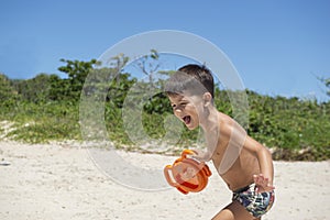Boy having fun and playing on the beach. Smile relaxed and cheerful