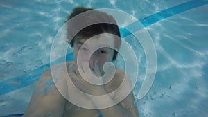 Boy having fun in the pool making bubbles underwater