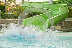 boy is having fun, while spending time in the aquapark. He is sliding down the water slide making a numerous splashes