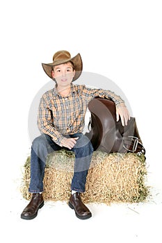 Boy on hay bale with saddle