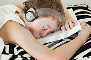 Boy with headphones asleep on top of textbook