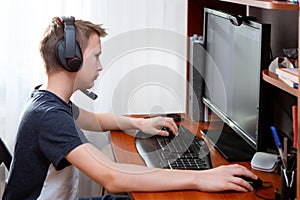 A boy in headphones in front of a computer does his homework. Distance learning in quarantine