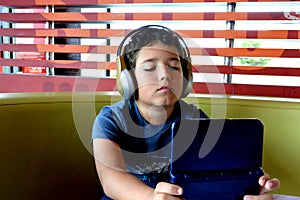 Boy with headphones is playing with electronic Game