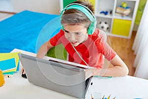 Boy in headphones playing video game on laptop