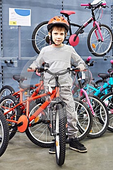 Boy in helmet chooses with bicycle in sport shop