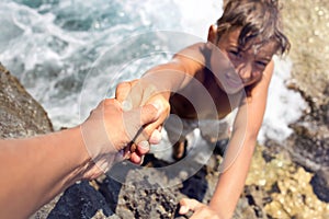 Boy helped by a friend to climb an inaccessible cliff photo