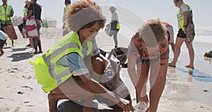 Boy helping female volunteer in cleaning beach 4k