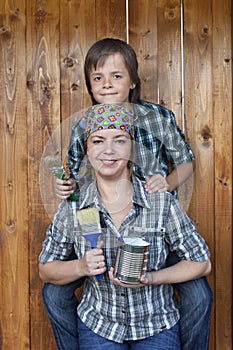 Boy helping his mother painting the tool shed