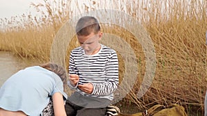 The boy helps the girl to strung worm on a fishing hook