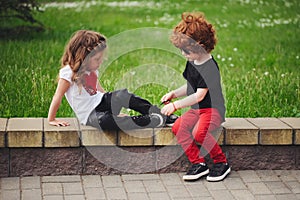 Boy helps little girl tie shoelaces