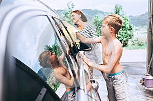 Boy helps to wash a car his mother