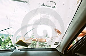 Boy helps to wash a car. Inside car camera view