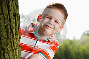 Boy hiding behind tree