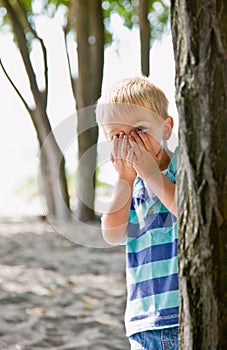Boy hiding behind tree