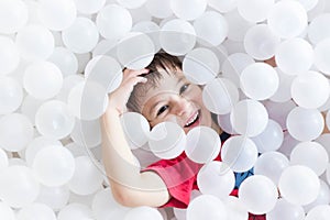 Boy hiding under white balls at the playground