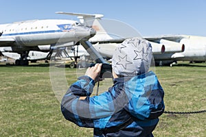 Boy with his camera is taking photos of old discommisioned airplanes,