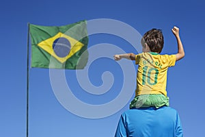 Boy and his father looking up at the Brazilian flag.