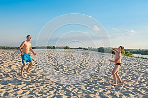 Boy with his father playing beach badminton on the beach, on a sunny day. Summer vacation, family beach games. Active lifestyle
