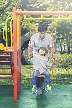 Boy and his father playing on the swing