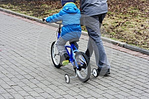 A boy with his father riding a Bicycle.