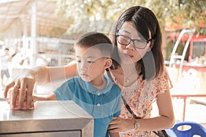 Boy and his mother all toghter donate by put money in donation box.