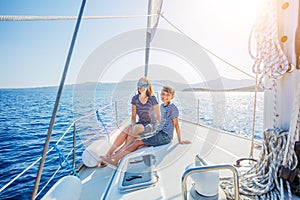 Boy with his mother on board of sailing yacht on summer cruise.