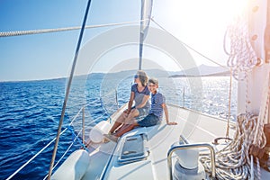 Boy with his mother on board of sailing yacht on summer cruise.