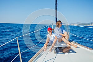 Boy with his mother on board of sailing yacht on summer cruise.