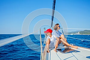 Boy with his mother on board of sailing yacht on summer cruise.